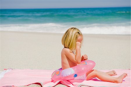 Girl sitting with an inflatable ring on the beach and crying Stock Photo - Premium Royalty-Free, Code: 6108-05865183