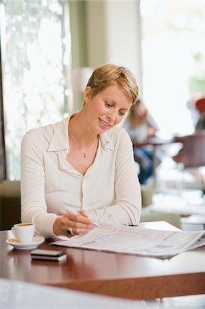 simsearch:6108-05856772,k - Businesswoman sitting in a restaurant and reading a financial newspaper Stock Photo - Premium Royalty-Free, Code: 6108-05865766