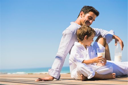 pictures of a family relaxing on the patio in summer - Man and his son drinking milk on the beach Stock Photo - Premium Royalty-Free, Code: 6108-05865868