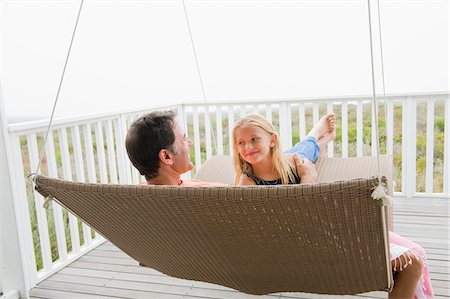 Girl sitting on a swing with her father Stock Photo - Premium Royalty-Free, Code: 6108-05865818