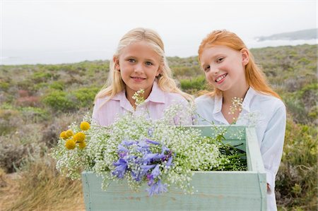 Two girls carrying a box of flowers and smiling Stock Photo - Premium Royalty-Free, Code: 6108-05865905
