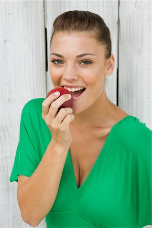 Woman eating an apple and smiling Stock Photo - Premium Royalty-Free, Code: 6108-05866173