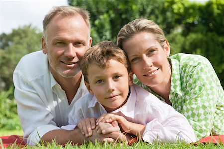 Boy with his parents lying on grass in a park Stock Photo - Premium Royalty-Free, Code: 6108-05866368