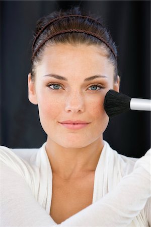 simsearch:6108-08637407,k - Portrait of a woman applying blusher on her face Stock Photo - Premium Royalty-Free, Code: 6108-05866514