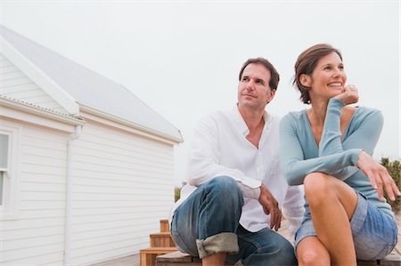 Couple assis en face d'une maison Photographie de stock - Premium Libres de Droits, Code: 6108-05866701