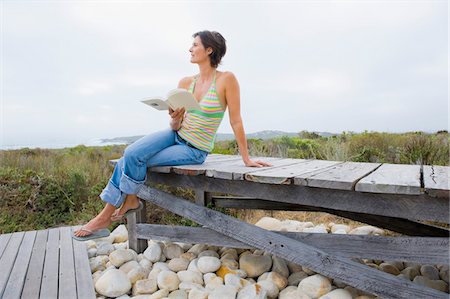 Femme assise sur un trottoir de bois et de lire un livre Photographie de stock - Premium Libres de Droits, Code: 6108-05866705