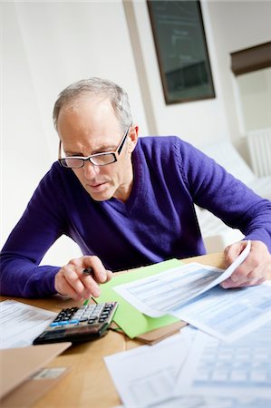Man using calculator and filling his tax form Stock Photo - Premium Royalty-Free, Code: 6108-05867347
