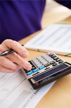 Man using calculator and filling his tax form Stock Photo - Premium Royalty-Free, Code: 6108-05867357