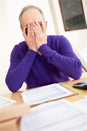 Man looking worried while filling his tax form Stock Photo - Premium Royalty-Free, Code: 6108-05867320