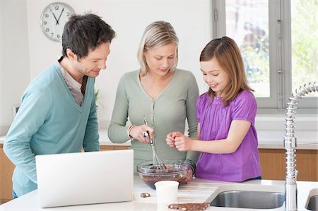 Family cooking with the recipe on a laptop Stock Photo - Premium Royalty-Free, Code: 6108-05867409