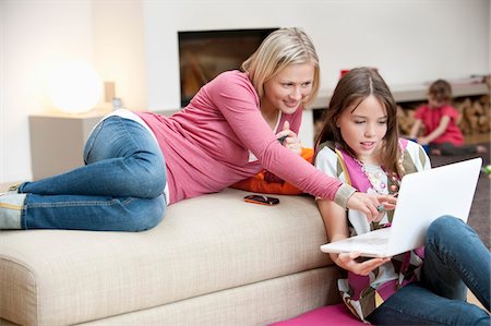 Woman assisting her daughter in using a laptop Stock Photo - Premium Royalty-Free, Code: 6108-05867416