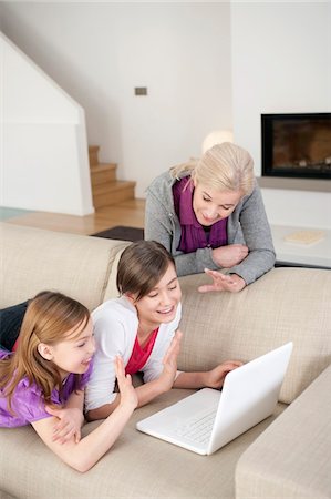 preteen girls looking older - Two girls using a laptop on a couch with their grandmother standing beside them Stock Photo - Premium Royalty-Free, Code: 6108-05867564