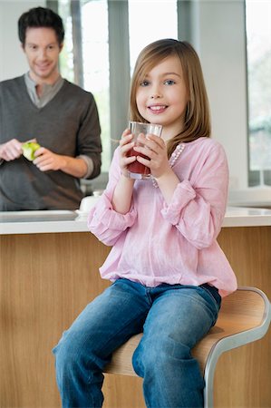 Girl drinking juice with her father standing behind her Stock Photo - Premium Royalty-Free, Code: 6108-05867520