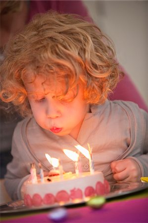 Boy blowing out candles on his birthday cake Stock Photo - Premium Royalty-Free, Code: 6108-05867673