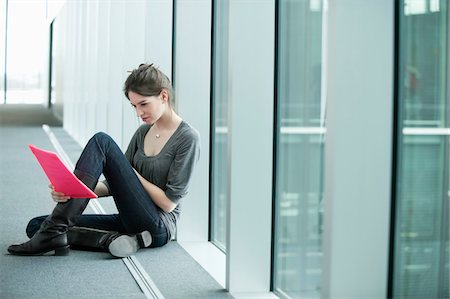 relaxation in the office - Businesswoman sitting in an office corridor and looking at a file Stock Photo - Premium Royalty-Free, Code: 6108-05868216