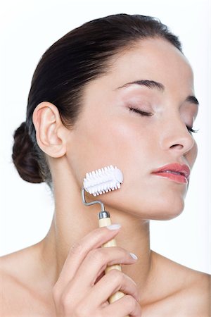 simsearch:6108-05869249,k - Young woman using facial massage roller Stock Photo - Premium Royalty-Free, Code: 6108-05869095