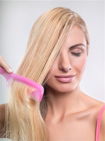 simsearch:6108-05869257,k - Young woman combing hair Stock Photo - Premium Royalty-Free, Code: 6108-05869254
