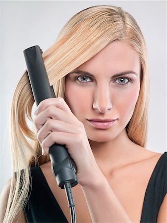 simsearch:6108-05869249,k - Young woman using hair straighteners Stock Photo - Premium Royalty-Free, Code: 6108-05869275