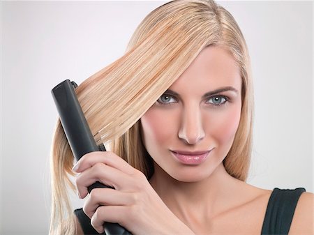 simsearch:6108-05869249,k - Young woman using hair straighteners Stock Photo - Premium Royalty-Free, Code: 6108-05869284