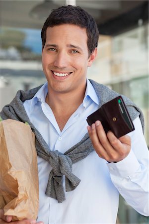 Portrait of a man showing empty wallet with paper bag full of vegetables Stock Photo - Premium Royalty-Free, Code: 6108-05869587