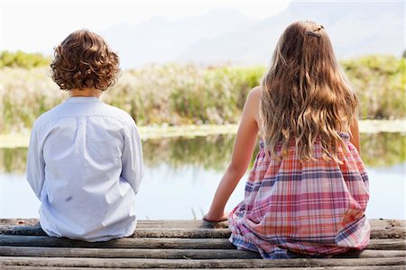 sitting on a dock - Rear view of siblings sitting together at a pier Stock Photo - Premium Royalty-Free, Code: 6108-05869516