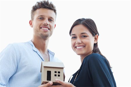 Portrait of a young couple holding a small model house Stock Photo - Premium Royalty-Free, Code: 6108-05869527