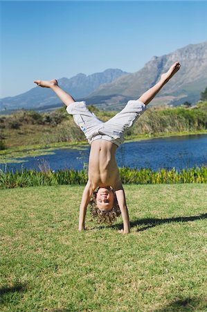 Cute little boy doing cartwheel against mountain Stock Photo - Premium Royalty-Free, Code: 6108-05869740
