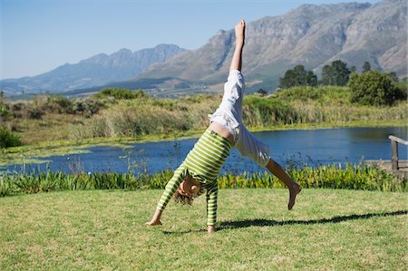 Cute little boy doing cartwheel against mountain Stock Photo - Premium Royalty-Free, Code: 6108-05869747