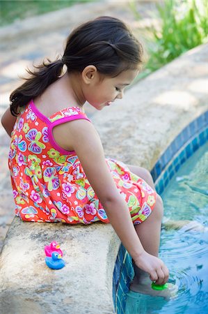 sitting poolside - Girl playing with rubber ducks at the edge of swimming pool Stock Photo - Premium Royalty-Free, Code: 6108-05869707