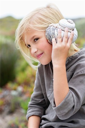 south africa and looking away - Close-up of a girl listening to a conch shell Stock Photo - Premium Royalty-Free, Code: 6108-05869737