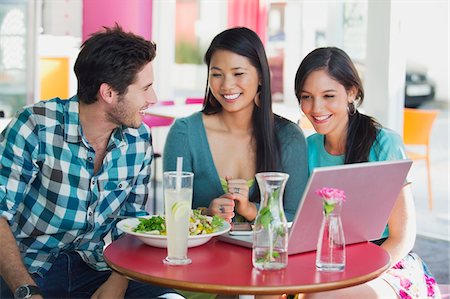 Friends using a laptop while eating food in a restaurant Stock Photo - Premium Royalty-Free, Code: 6108-05869853