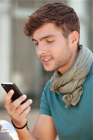 sending - Young man text messaging on a mobile phone Foto de stock - Sin royalties Premium, Código: 6108-05870106