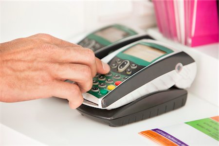 Sales clerk using a credit card reader at counter Stock Photo - Premium Royalty-Free, Code: 6108-05870348