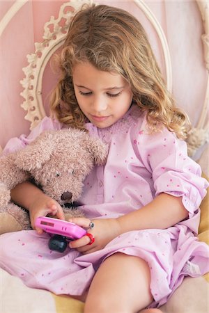 simsearch:6108-06905230,k - Cute little girl playing video game on the bed Stock Photo - Premium Royalty-Free, Code: 6108-05870447