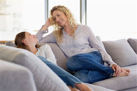 simsearch:6108-05872072,k - Mid adult woman and her daughter sitting on a couch and smiling Stock Photo - Premium Royalty-Free, Code: 6108-05870418