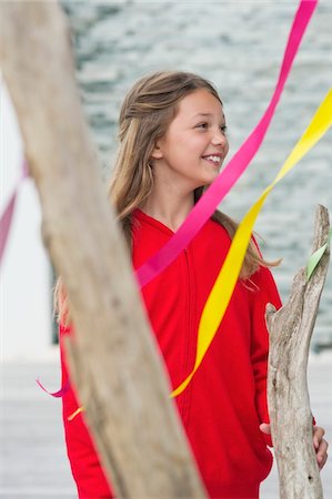 ribbon (material) - Girl standing near a decorated tree and smiling Stock Photo - Premium Royalty-Free, Code: 6108-05870618