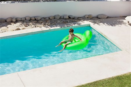 Boy sitting on inflatable ring in swimming pool Stock Photo - Premium Royalty-Free, Code: 6108-05870911