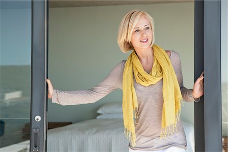 Woman standing at door and smiling Stock Photo - Premium Royalty-Free, Code: 6108-05871134