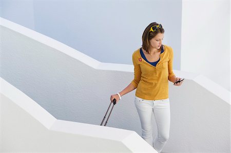 stairs casual - Woman using mobile phone while walking down stairs Stock Photo - Premium Royalty-Free, Code: 6108-05871254