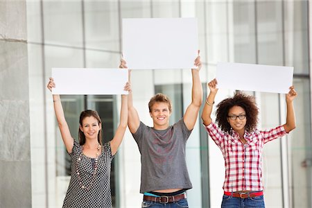 Portrait of three friends holding blank placards Stock Photo - Premium Royalty-Free, Code: 6108-05871363