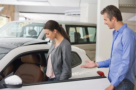 Young woman checking car from inside while man holding the door Stock Photo - Premium Royalty-Free, Code: 6108-05871423