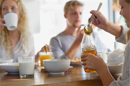 Family eating breakfast at home with focus on a girl taking out honey Foto de stock - Sin royalties Premium, Código: 6108-05871666