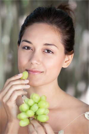 Portrait of a young woman eating grapes Stock Photo - Premium Royalty-Free, Code: 6108-05871757