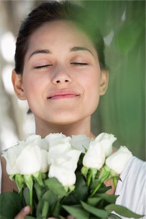 Beautiful young woman holding bunch of white flowers with her eyes closed Stock Photo - Premium Royalty-Free, Code: 6108-05871725