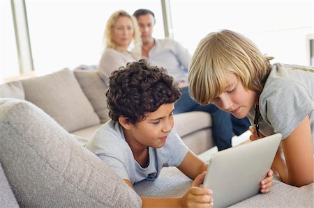 simsearch:6108-05872043,k - Brothers using a digital tablet with their parents looking at them Stock Photo - Premium Royalty-Free, Code: 6108-05872049
