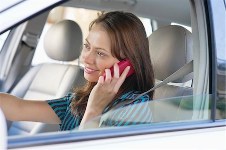 driving car side - Beautiful young woman talking over mobile phone while driving a car Stock Photo - Premium Royalty-Free, Code: 6108-05872176