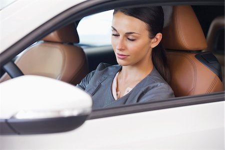 Beautiful young woman sitting in car with her eyes closed Stock Photo - Premium Royalty-Free, Code: 6108-05872243