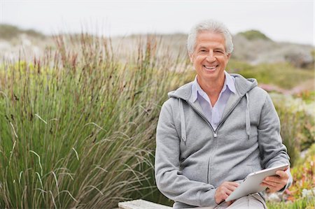 Happy senior man using a digital tablet Stock Photo - Premium Royalty-Free, Code: 6108-05872381