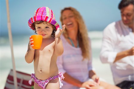 families playing on the beach - Girl drinking juice with her parents in the background Stock Photo - Premium Royalty-Free, Code: 6108-05872521
