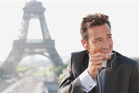 Businessman using a hands-free device with the Eiffel Tower in the background, Paris, Ile-de-France, France Stock Photo - Premium Royalty-Free, Code: 6108-05872888